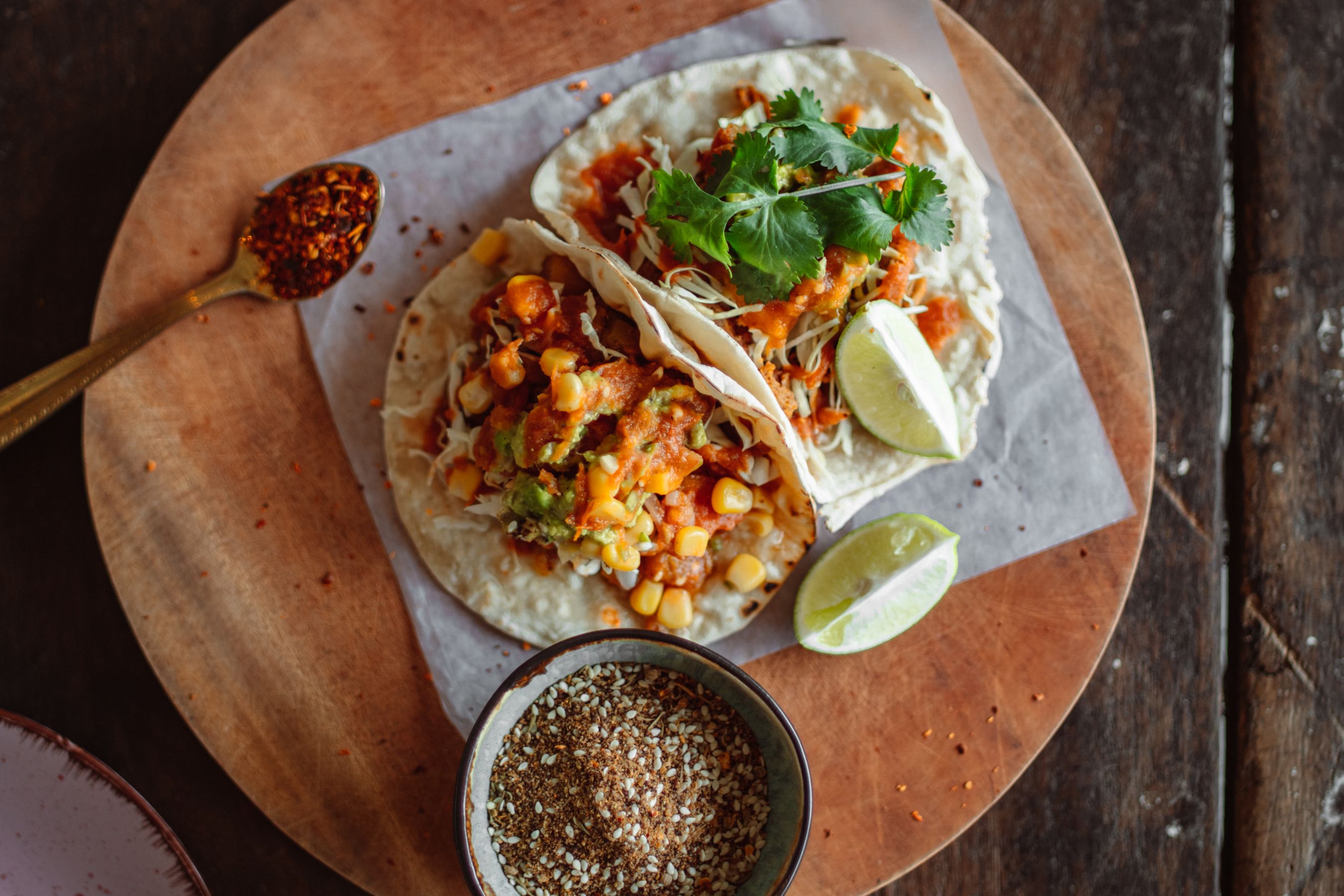 Overhead view of Mexican breakfast tacos on a wooden plate, lime and salsa alongside — the reference standard for every sauce.